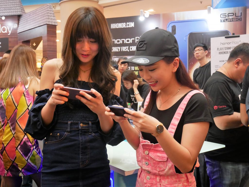 Happy gamers playing with the honor Play smartphone 